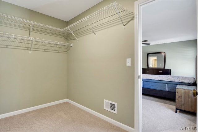 spacious closet with light carpet and ceiling fan