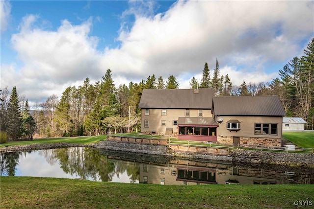 back of property featuring a lawn and a water view