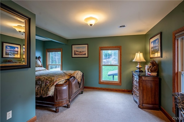 bedroom with light colored carpet and multiple windows