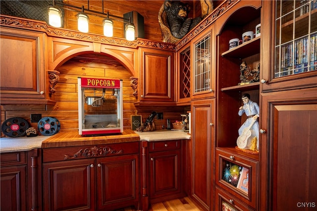 bar with wood walls, light wood-type flooring, and decorative light fixtures