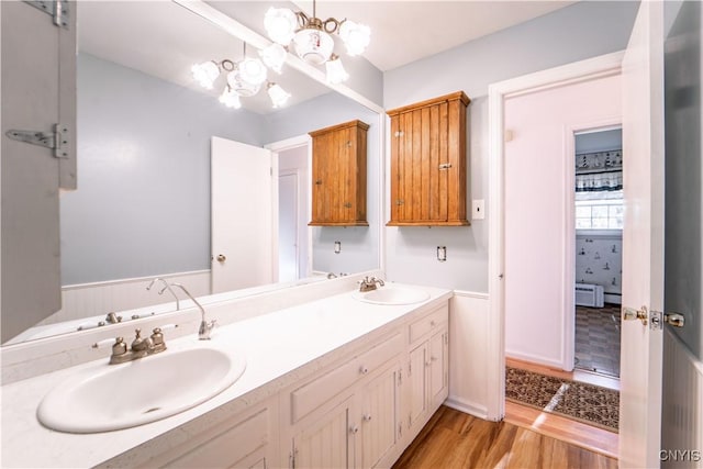 bathroom featuring a baseboard radiator, wood-type flooring, vanity, and an inviting chandelier