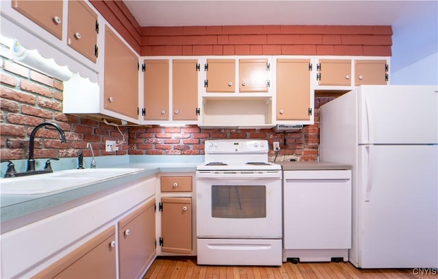 kitchen with cream cabinetry, white appliances, brick wall, light hardwood / wood-style flooring, and sink