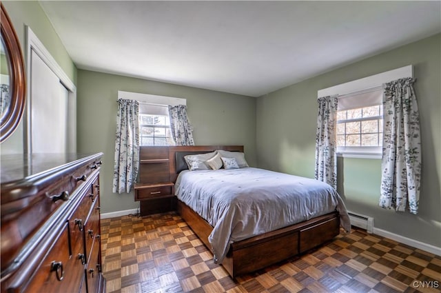 bedroom with baseboard heating and dark parquet flooring