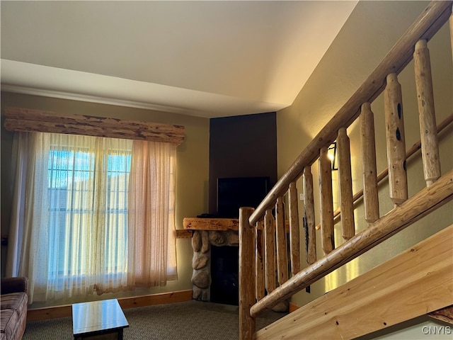 staircase featuring a stone fireplace and carpet