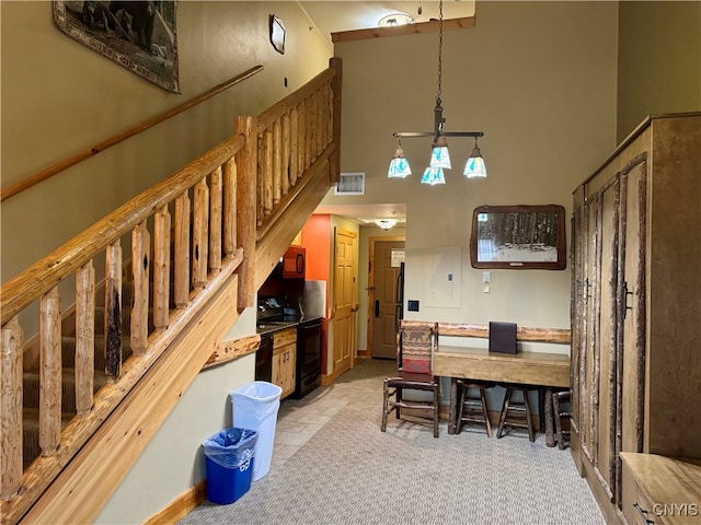 kitchen featuring hanging light fixtures, light colored carpet, black appliances, and a high ceiling