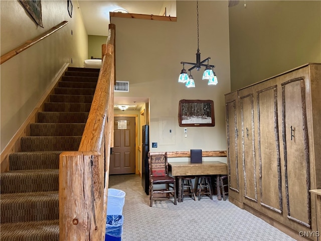 interior space featuring high vaulted ceiling, a notable chandelier, electric panel, and carpet