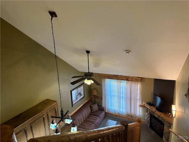 carpeted living room featuring a stone fireplace, lofted ceiling, and ceiling fan