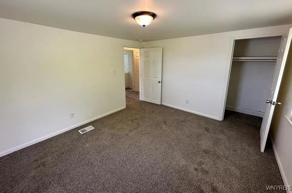 unfurnished bedroom with a closet and dark carpet