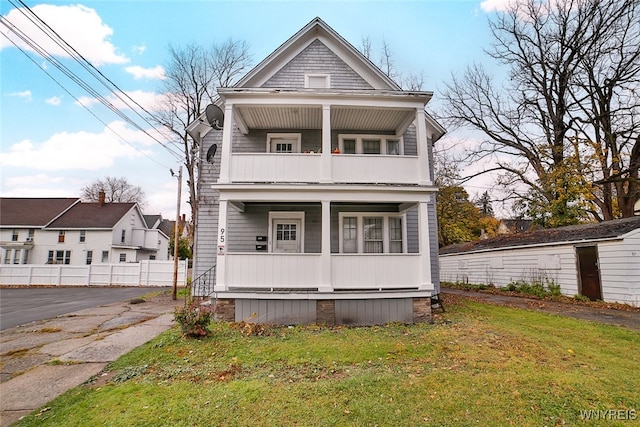 view of front facade featuring a porch, a front yard, and a balcony