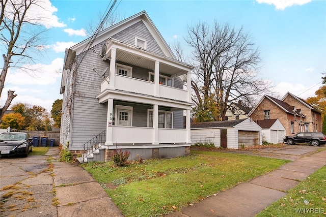 view of front of home with an outbuilding, a garage, a front lawn, and a balcony