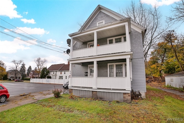 view of front of property with a front lawn, a balcony, and covered porch