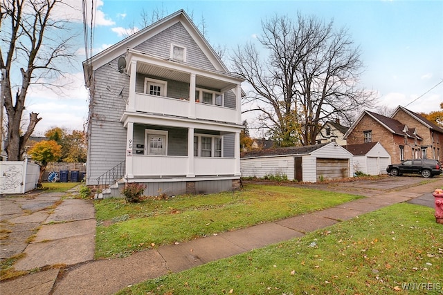 view of front of property featuring a balcony, a garage, an outdoor structure, and a front lawn