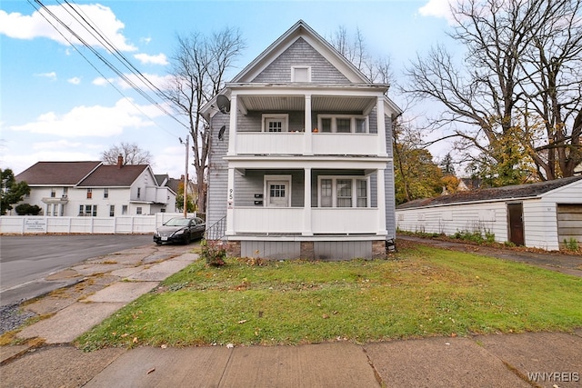 view of front facade featuring a front lawn, a balcony, and covered porch