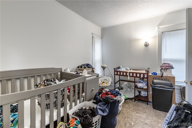 bedroom featuring a textured ceiling, carpet flooring, ornamental molding, and a crib