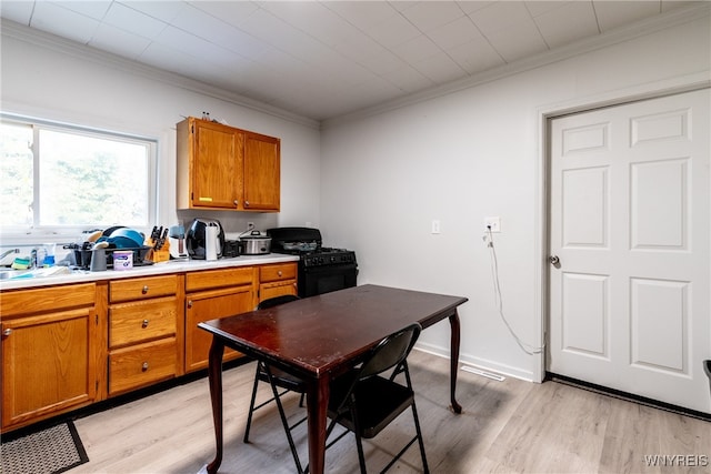 kitchen with black range with gas stovetop, sink, ornamental molding, and light wood-type flooring