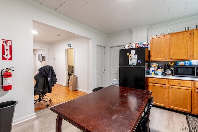 kitchen featuring black appliances, light wood-type flooring, decorative backsplash, and ornamental molding