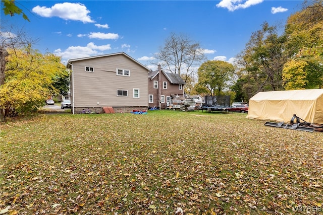 back of property with a lawn and a storage shed