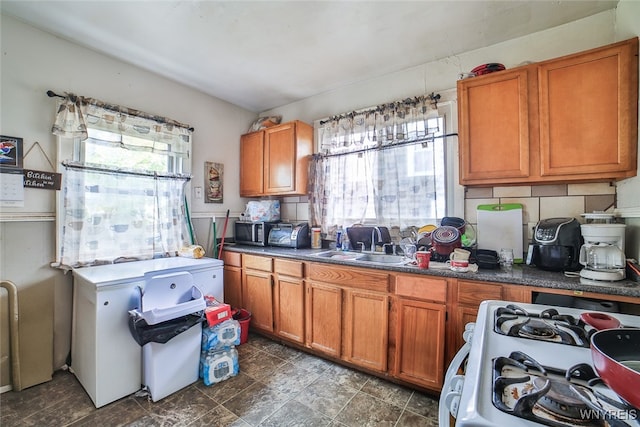 kitchen with a wealth of natural light, sink, backsplash, and white range with gas stovetop