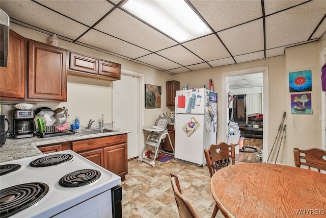 kitchen with a paneled ceiling, white appliances, and sink