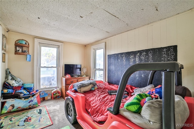 carpeted bedroom featuring multiple windows and wooden walls