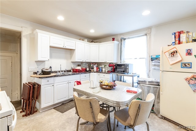 kitchen with white appliances, white cabinetry, sink, and light tile patterned flooring