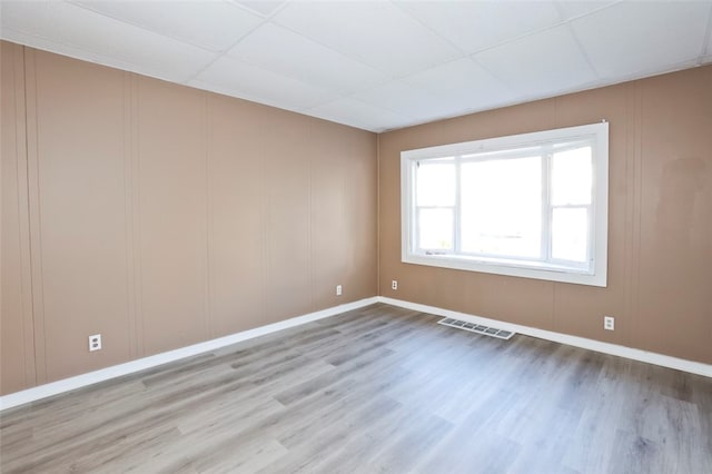 spare room with a paneled ceiling and hardwood / wood-style flooring