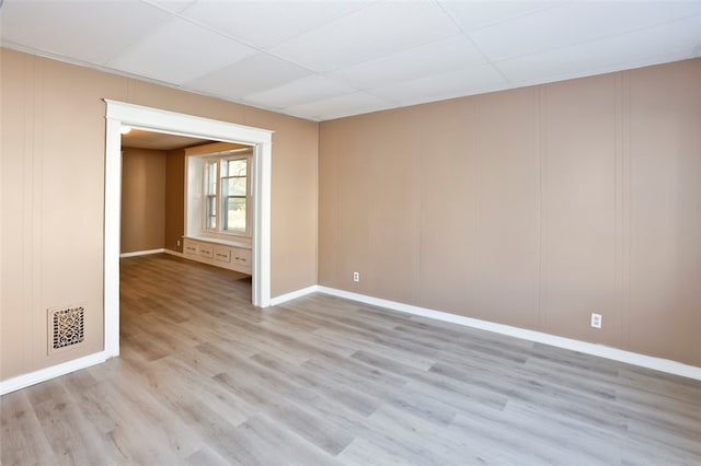 spare room featuring light hardwood / wood-style flooring and a drop ceiling