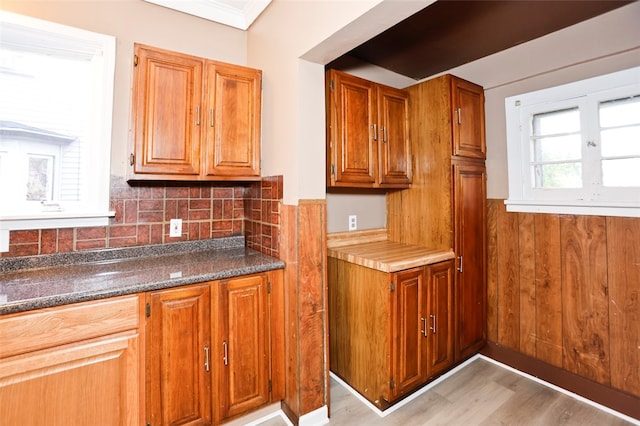 kitchen with tasteful backsplash, dark stone countertops, and light wood-type flooring