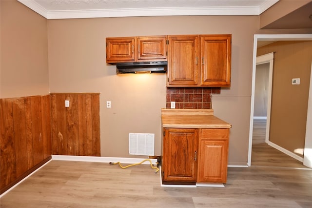 kitchen with crown molding, light hardwood / wood-style flooring, and wood walls