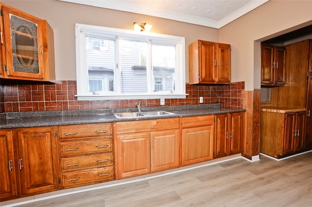 kitchen featuring backsplash, light hardwood / wood-style floors, ornamental molding, and sink