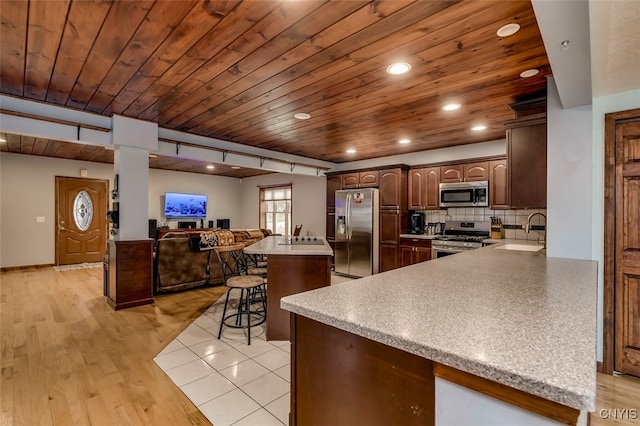 kitchen with stainless steel appliances, wooden ceiling, a breakfast bar, kitchen peninsula, and light wood-type flooring