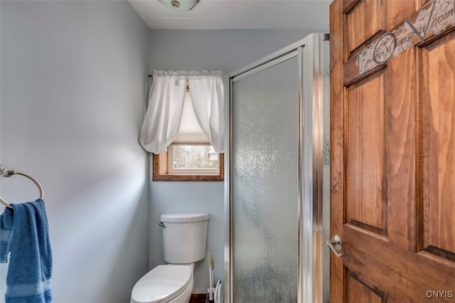 bathroom featuring a shower with door and toilet