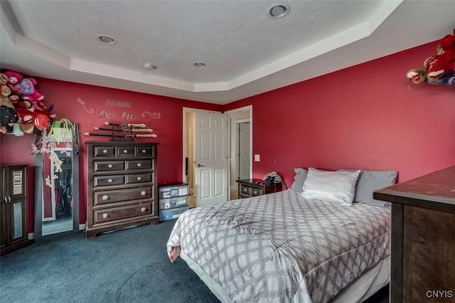 bedroom featuring dark colored carpet and a tray ceiling