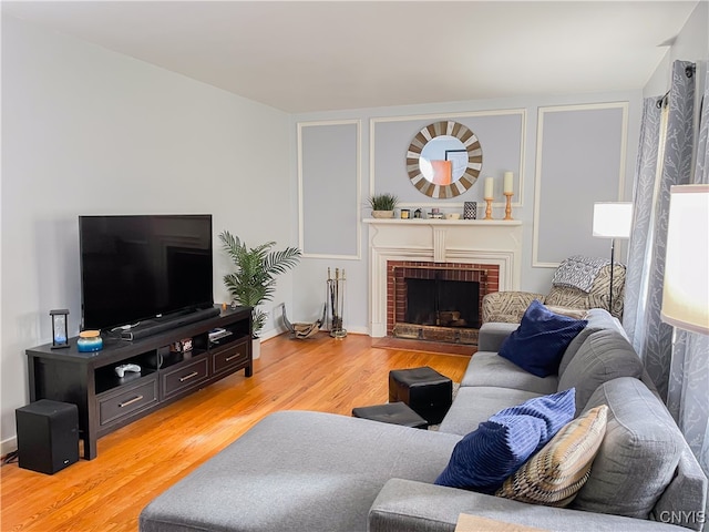 living room with hardwood / wood-style floors and a brick fireplace