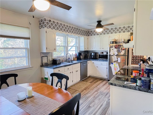 kitchen featuring stainless steel appliances, white cabinetry, sink, ceiling fan, and light hardwood / wood-style flooring