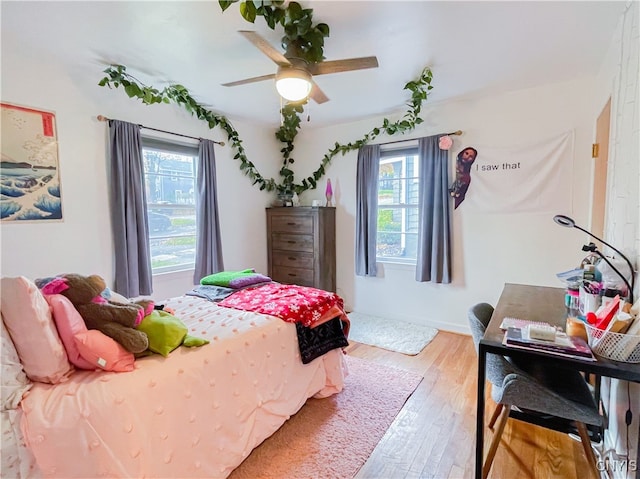 bedroom with ceiling fan, multiple windows, and light wood-type flooring