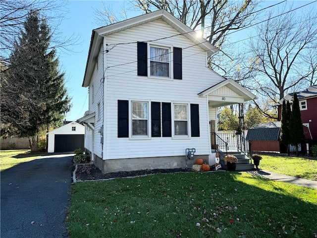 view of property featuring a front lawn, a garage, and an outbuilding