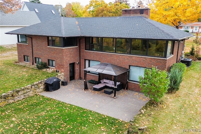 rear view of property featuring central air condition unit, a lawn, a sunroom, and a patio area