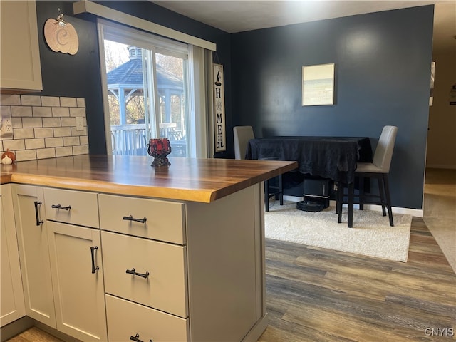 kitchen featuring white cabinets, wood counters, dark wood-type flooring, and backsplash