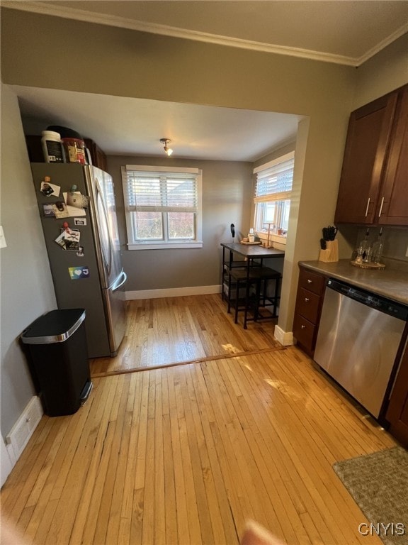 kitchen with dark brown cabinets, stainless steel appliances, crown molding, and light hardwood / wood-style flooring