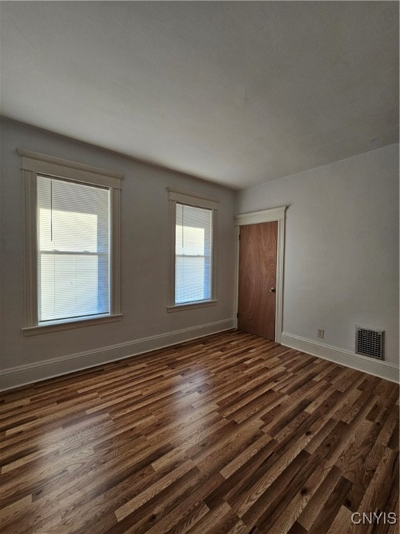 empty room featuring a wealth of natural light and dark hardwood / wood-style flooring