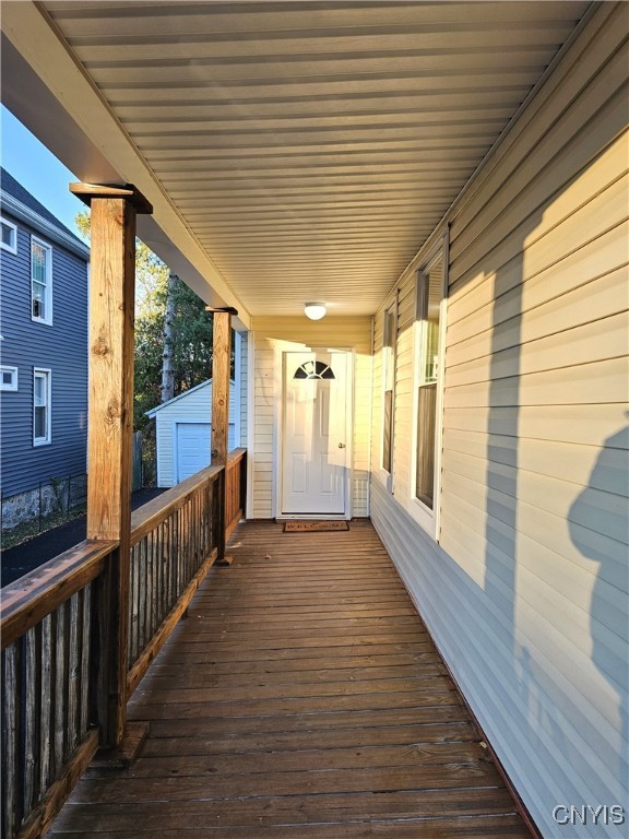 wooden deck featuring a garage, a porch, and an outbuilding