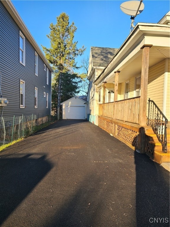 view of property exterior with covered porch, a garage, and an outdoor structure