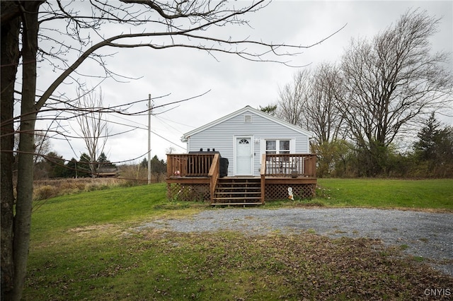 rear view of property featuring a wooden deck and a yard