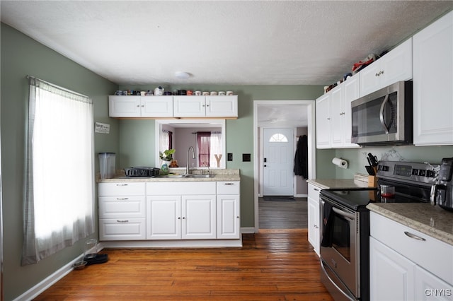 kitchen featuring white cabinetry, appliances with stainless steel finishes, wood-type flooring, and sink