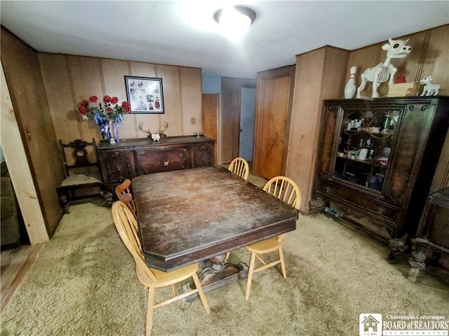 carpeted dining area with wood walls