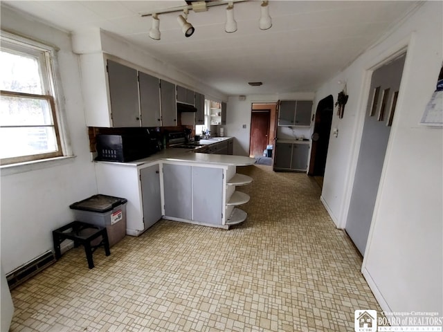 kitchen featuring sink, a breakfast bar, kitchen peninsula, rail lighting, and range