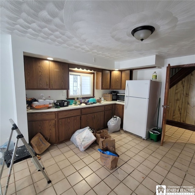 kitchen featuring light tile patterned floors, light countertops, and freestanding refrigerator