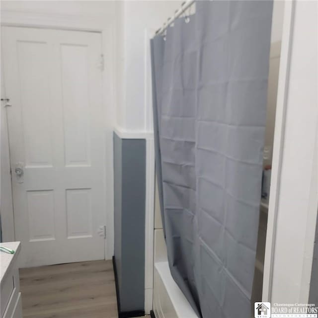 bathroom with vanity, shower / bathtub combination with curtain, and wood finished floors