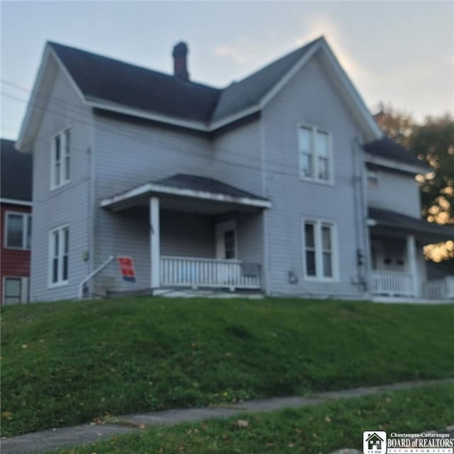 view of front of home with a porch and a front yard